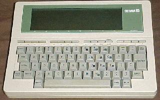 The Kyocera KC-85 is a notebook sized unit with a full-size keyboard and 8x40 screen.  This image shows the top/front of the machine.